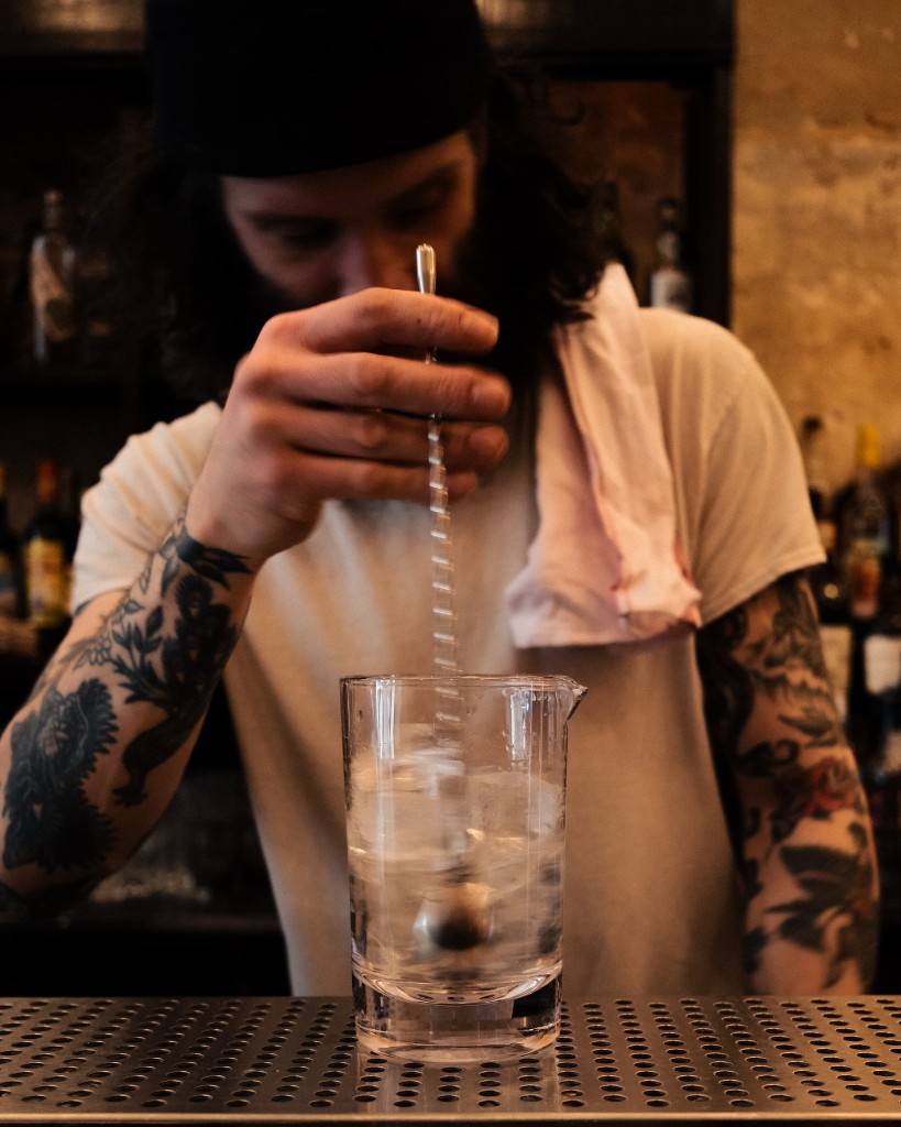 Bartender stirring a cocktail behind the bar at The Virginia Bar