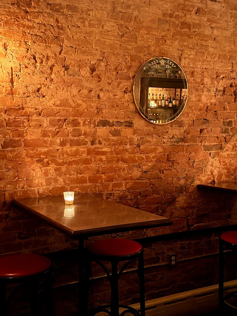 Candlelit high-top against exposed brick with mirror reflecting the bar